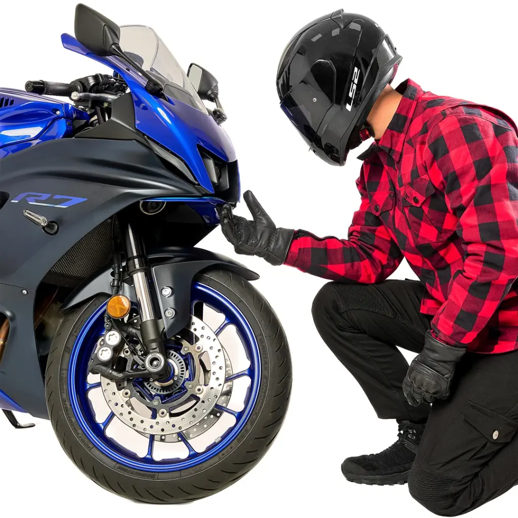 Alfa Thrust Casper Steel Red – koszula motocyklowa, motocyklista w czerwonej flaneli klęczący przy niebieskim motocyklu.